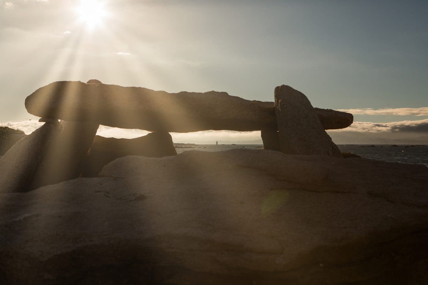 Dolmen megalítico del Islote de Areoso a contraluz al atardecer, con la Ría de Arousa al fondo